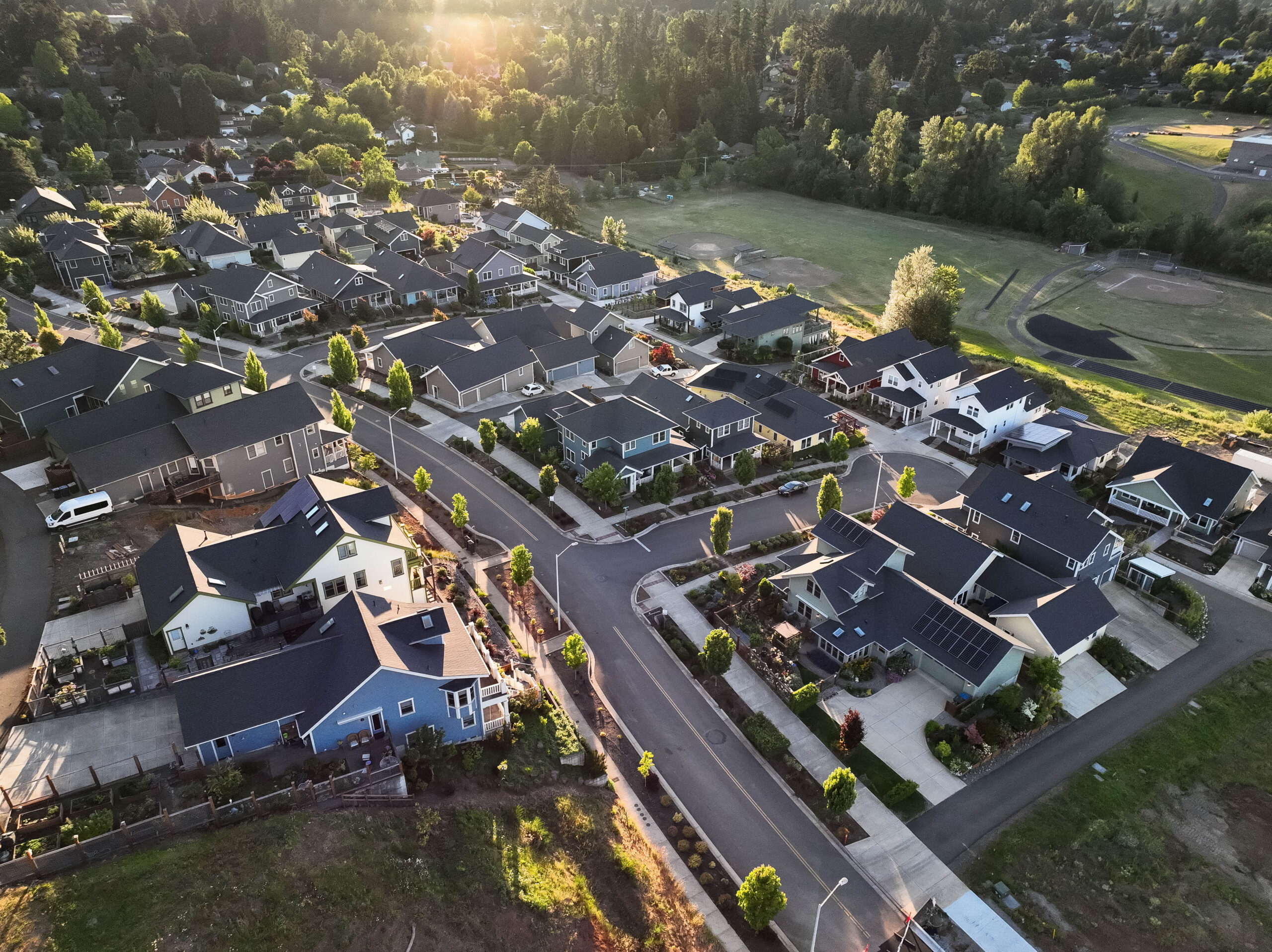 Aerial view of Olsen Communities neighborhood at golden hour with custom homes, tree-lined streets and solar panels
