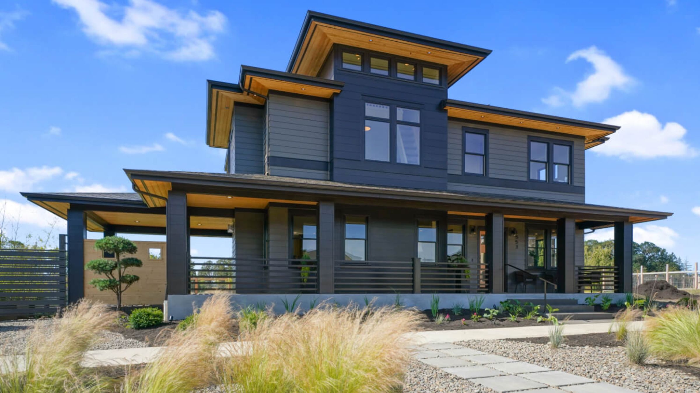 Modern custom home exterior with wood-accented eaves and covered porch, shaped by the design questions Olsen Communities asks before building in the Willamette Valley.